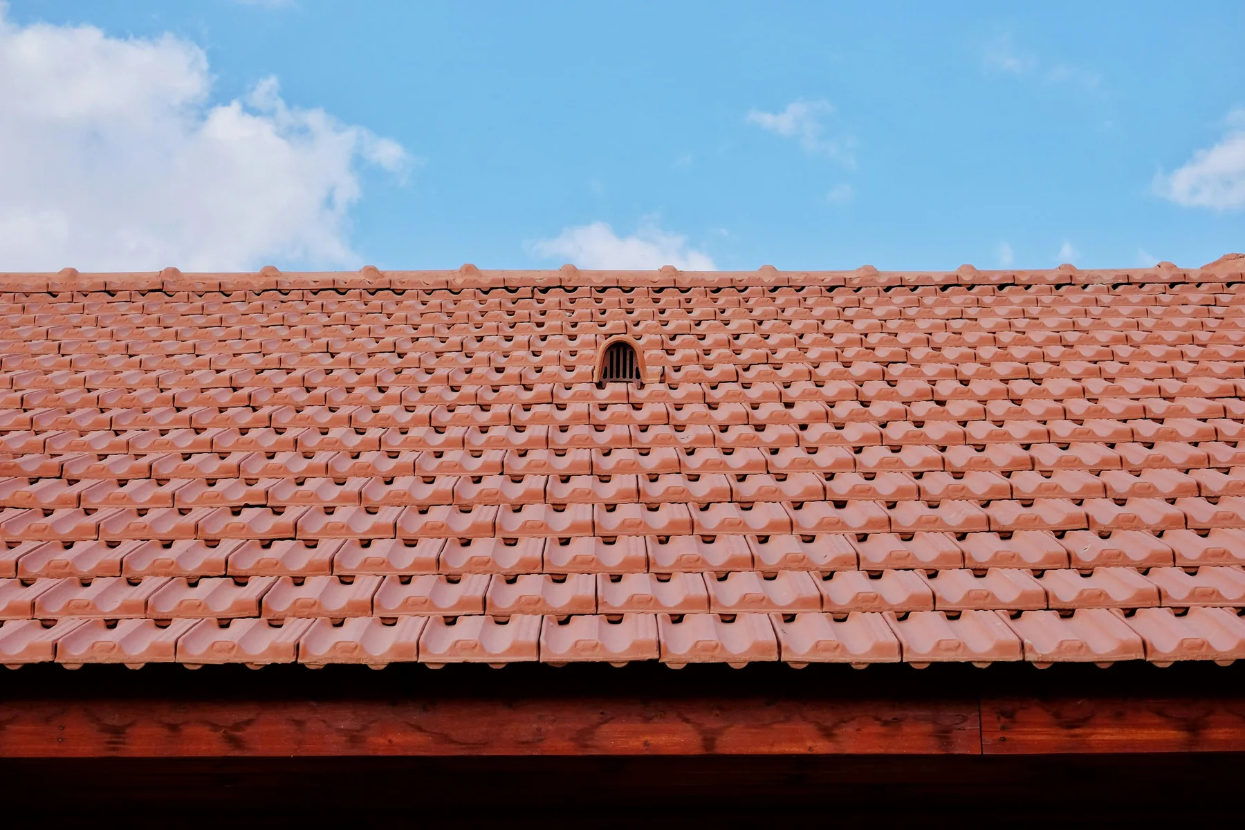 Clean terracotta roof under a bright blue sky.